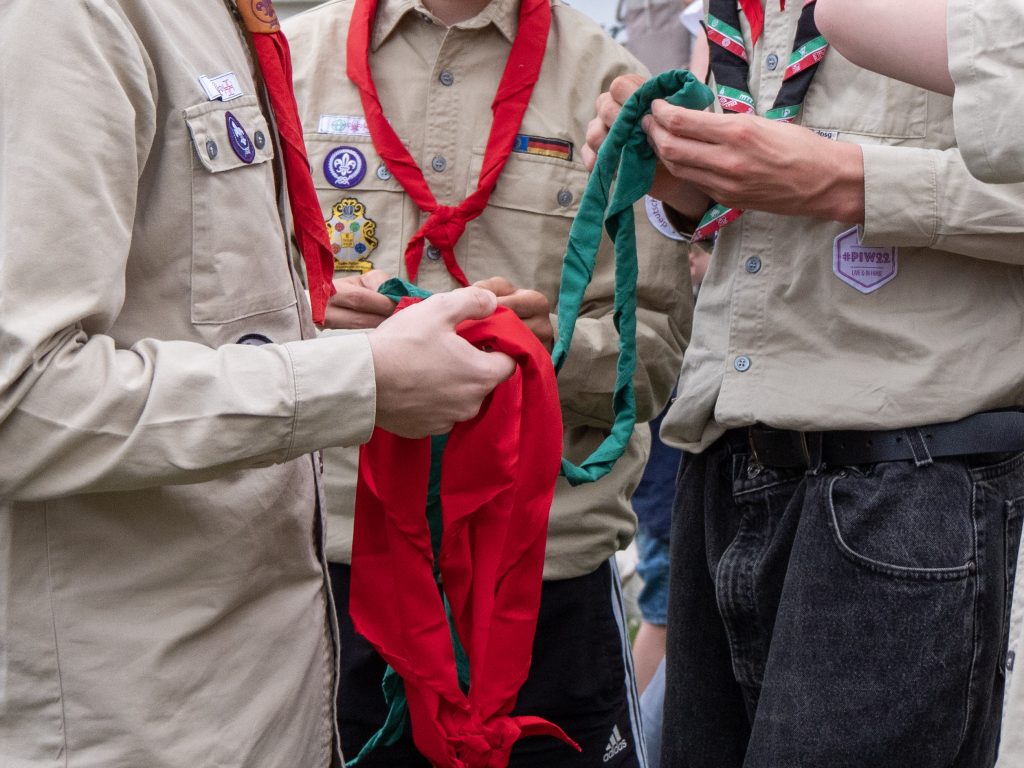 Hier sind 3 Pfadfinder zusehen. Das Bild ist auf die Oberkörper zu geschnitten.. Es sind keine Köpfe zu sehen. Die Pfadfinder Tauschen ein grünes Pfadituch gegen ein Rovertuch.
Ein Pfadi wird als neuer Rover in die Roverrunde aufgenommen.